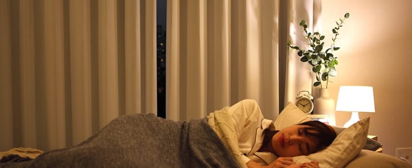 ベッドでぐっすり眠る女性とカーテン